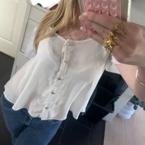 Vit blus med knappar - Blusen har korta ärmar och en lös passform, perfekt till jeans eller kjol. Storlek M men sitter som S