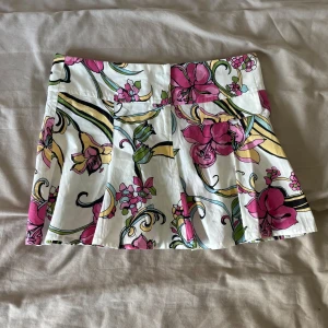 Vit blommig kjol från Boattik - Mini kjol med färgglatt blommönster i rosa, gul och grön på vit botten från Boattik. 