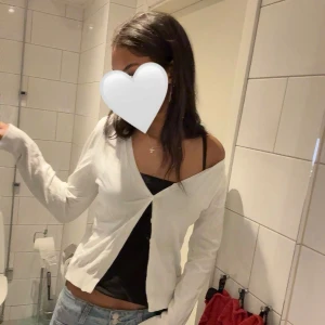 Vit kofta - Säljer en vit kofta med knappar framtill. Koftan är långärmad och har en croppad passform som sitter snyggt över axlarna. Perfekt att styla över ett linne eller topp.