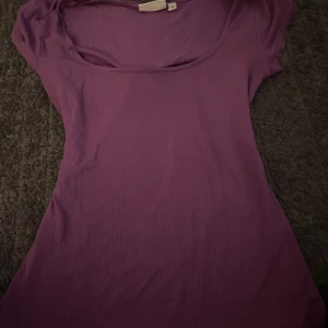 Lila ribbad topp från Kappahl - Säljer en lila ribbad topp från Kappahl i storlek S. Toppen har korta ärmar och en rund, lite djupare halsringning. Perfekt att styla till jeans eller kjol för en enkel och snygg look.