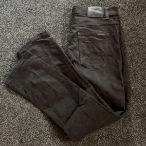 Svarta Nudie Jeans - Säljer ett par svarta Nudie Jeans med klassisk femficksdesign och knäppning med knappar. Jeansen är nästan nya och endast använda fåtal gånger. Topp skick. Hör av er vid fler frågor och funderingar 🔥🔥