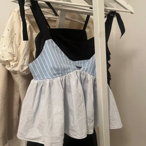 Blå och svart linnetopp med knytband - Säljer en söt linnetopp med svart överdel och blåvit randig nederdel. 