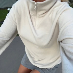 Vit fleecejacka med halv dragkedja - Mysig vit fleecetröja från LXA med halv dragkedja och hög krage. Tröjan finns inte mer då företaget lagt ner. I bra skick (skriv för fler bilder)