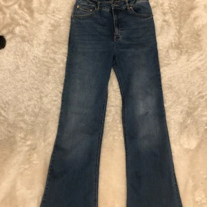 Blå bootcut jeans från Pull&Bear - Säljer ett par klassiska blå bootcut jeans från Pull&Bear. Jeansen har hög midja, fem fickor och stängs med dragkedja och knapp. Perfekta för dig som gillar en tidlös och avslappnad stil. Pris kan diskuteras 