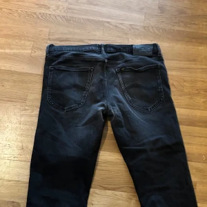 Svarta jeans från Lee - Säljer ett par svarta jeans från Lee med klassisk femficksdesign och raka ben. Jeansen har normal passform och är tillverkade i denim. Perfekta för dig som gillar en tidlös stil.