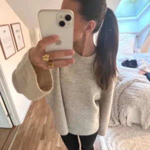 Beige stickad tröja från Gina tricot  - Mysig beige stickad tröja från Gina tricot med rund halsringning och breda ärmar. Tröjan har en rak passform och ribbade muddar vid ärmslut och nederkant. Perfekt för lager-på-lager under kyliga dagar.