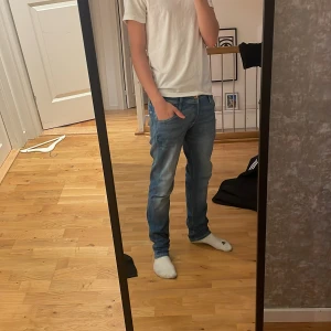 Blå jeans från Jack & Jones - Säljer ett par klassiska blå jeans från Jack & Jones. Jeansen har fem fickor, normal passform och raka ben. De är tillverkade i denim och har en snygg tvättad look med ljusare partier på låren och bak. Perfekta till vardags! Väldigt bra skick.
