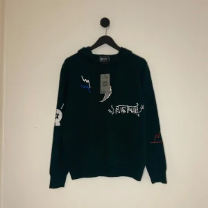 Zadig Voltaire Hoodie - HELT NY 100% KASHMIR! Säljer en mörkgrön hoodie från Zadig & Voltaire med broderade grafiska detaljer och texten 'ART IS TRUTH' framtill. Tröjan har huva och långa ärmar, samt coola färginslag i blått, rött och vitt. Perfekt för dig som gillar streetstyle. Storlek S men passar Xs.