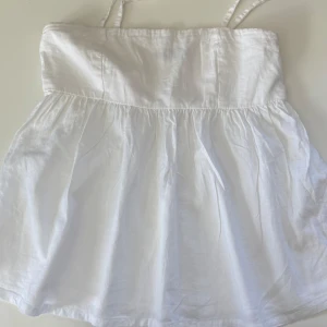 Vit linnetopp från Bik Bok - Supersöt vit linnetopp från Bik Bok med smala justerbara axelband (avtagbara) och volang nedtill. Sparsamt använd i stolen S. ⭐️🌸