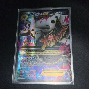 M Aggron EX - Coolt och glittrande Pokémonkort med M Aggron EX! Perfekt för samlare och fans av Pokémon. Kortet har en färgstark design och är i bra skick, redo att ta din samling till nästa nivå.