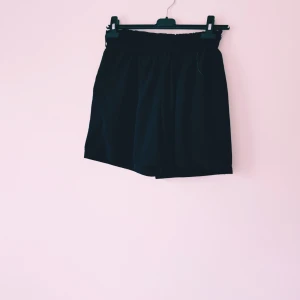 Svarta shorts från XL - Svarta shorts med elastisk midja och avslappnad passform. Tillverkade i ett mjukt tyg som känns svalt och skönt. Perfekta för varma dagar när du vill ha något enkelt och stilrent. Klassisk look utan mönster eller extra detaljer.  Lite trasig på mudden (se extra bild) annars fint skick