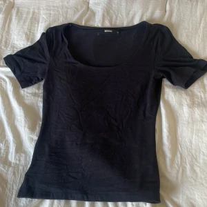 Svart topp med rund hals från BikBok - En enkel svart topp från BikBok i storlek XS. Tunn och mjuk känsla, sitter figurnära och passar till vardagen eller annat tillfälle!Endast använd 3-4 pga för liten🥲Pris kan diskuteras