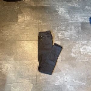 Svarta jeans Tiger of Sweden - Snygga svarta jeans från Tiger of Sweden med klassisk femficksdesign och gul broderad logga på myntfickan. Jeansen har smal passform och är tillverkade i stretchig bomullsblandning för en bekväm känsla hela dagen. Storlek 28-30