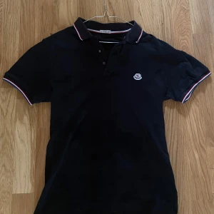 Svart Moncler pikétröja med logga - Svart piké från Moncler, gott skick och äkta. Storlek M