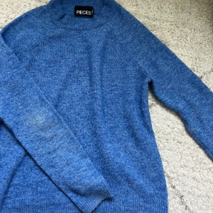 Blå stickad tröja  - Mysig blå stickad tröja från Pieces i storlek XS. Tröjan har rund halsringning, långa ärmar och ribbade muddar vid hals, ärmslut och nederkant. Perfekt för lager-på-lager och chill dagar.