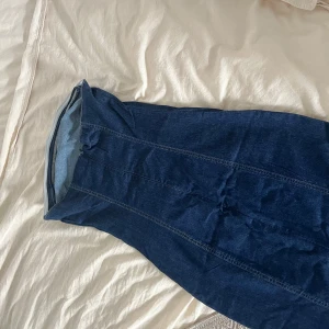 Mörkblå lång jeanskjol med slits - Säljer en snygg mörkblå lång jeanskjol med markerade sömmar och en slits framtill. Kjolen har klassisk denimlook och är perfekt för dig som gillar en tidlös och chill stil. Passar till sneakers eller boots för en cool vibe.