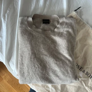 Beige crewneck tröja Rose & Born - Snygg beige crewneck tröja från Rose & Born i en lyxig mix av ull och kashmir. Tröjan har ribbade muddar vid ärmslut, hals och nederkant samt en klassisk, stilren look. Perfekt för dig som gillar en clean och tidlös vibe.