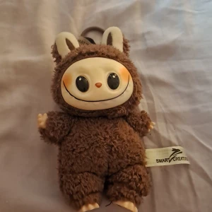 Labubu  - Bilderna visar en söt och fluffig labubu med stora ögon 