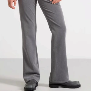 Grå bootcut kostymbyxor - Snygga grå kostymbyxor med bootcut-silhuett och klassisk passform. Byxorna har en stilren look med diskreta fickor och är tillverkade i ett mjukt material som ger en dressad känsla. Perfekta att matcha med stickad tröja eller skjorta.