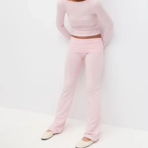 Ljusrosa mjukisbyxor från Gina Tricot - Supersköna ljusrosa mjukisbyxor från Gina Tricot i stretchigt bomullsmaterial. Byxorna har en slim passform upptill och lätt utsvängda ben, perfekt för en chill och trendig look. Midjan är låg och modellen är enkel utan fickor eller detaljer.