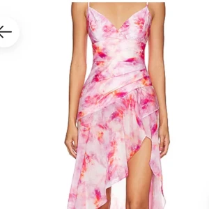 Rosa långklänning från Bardot - Superfin långklänning från Bardot i rosa och rött mönster. Klänningen har smala axelband, v-ringning och asymmetrisk volangkjol med slits. Lätt och flowigt material, perfekt för sommarens alla tillfällen. Dragkedja i sidan för enkel påklädning. Köpt från revolve för 1500 kr 
