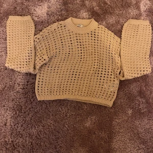 Beige stickad tröja från JDY - Säljer en beige stickad tröja från JDY i storlek XS. Tröjan har ett coolt hålmönster över hela och ribbade muddar vid hals, ärmslut och nederkant. Perfekt för dig som gillar en unik och trendig look med lite loose passform.