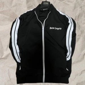 Palm Angels Svart - Palm Angels Track Top - svart med vita stripes. Endast Tröjan. Bra Skick och 100% Äkta. Strl S. Perfekt För Hösten.