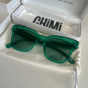 CHIMI #005 Aqua - Snygga gröna solglasögon från CHIMI, modell #005 Aqua. Rektangulär form med transparent grön båge och matchande gröna linser. Kommer med originalfodral och putsduk. Perfekt för dig som vill sticka ut med färg och stil. Aldrig använda.