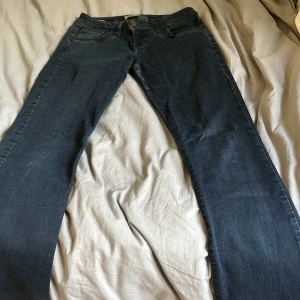 Mörkblå jeans med raka ben - Mörkblå jeans med klassisk femficksdesign och raka ben. Jeansen har diskreta slitningar vid bensluten och bakfickor med broderad detalj. Perfekta för en avslappnad stil och tillverkade i mjukt denimtyg. Storlek 27/32