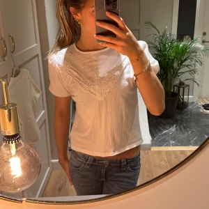 Vit blus med spetsdetaljer - Supersöt vit blus med puffiga korta ärmar och snygga spetsdetaljer framtill. Blusen har en lätt struktur i tyget och en liten knapp i nacken. Blusen är i strl 134/140 och på bilderna der du hur den sitter på mig som vanligtvis har xs.