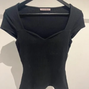 Svart ribbad topp från Anna Field - Svart ribbad topp från Anna Field med v-ringad hals och korta ärmar. Snygg, figurnära passform och stretchigt material som gör den bekväm och enkel att styla till olika looks.