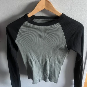 Svart och grå ribbad långärmad tröja från brandy melville  - Säljer en långärmad tröja med svart ribbade ärmar och grå ribbad kropp. Tröjan har en rund halsringning och är slim i passformen. Tröjan är köpt i one size men skulle säga att den är nära S/xs