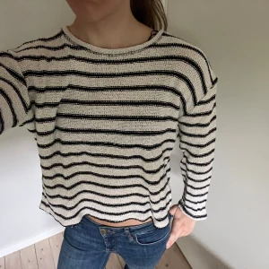 Randig stickad tröja - Snygg stickad randig tröja med svarta och vita ränder. Tröjan har en avslappnad passform, rund hals och långa ärmar.