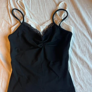 Svart och vitt linne - säljer 2 linnen som är svart och vit med en slitt längst ner på båda sidorna, säljer dom för att rensa ut garderoben och har aldrig använt nån av dom 