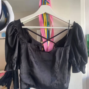 Topp med knytning - Superfin svart kroppad topp med knytning där bak. Osäkert vart den är ifrån då kappen är bortklippt. Skulle säga att den är i storlek XS.