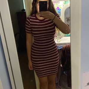 Vinröd och vit randig ribbad klänning - Säljer en kort, tight klänning från H&M i vinrött med vita ränder. Klänningen är ribbad, har rund hals och korta ärmar. Materialet är mjuk bomull med lite stretch för en skön passform. Perfekt för dig som gillar en enkel men snygg look. Otroligt skön klänning med strechigt materal, ibte obekväm nånstans. Använd 1-2 gånger bara❤️