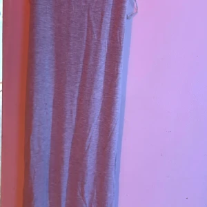 Grå långklänning med smala axelband - Supersnygg grå långklänning från Gina Tricot med smala axelband och figurnära passform. Jag har bara använt den två gånger, köpte den för ungefär tre veckor sedan men har knappt använt den. Klänningen är ärmlös, har en enkel och stilren design i mjukt, supermysigt bomullsmaterial. Storlek XS, perfekt för dig som gillar minimalistisk stil och bekväma plagg