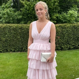 Balklänning  - Säljer min superfina balklänning från Bubbleroom i storlek 38🌸Volangerna är i flera lager vilket jag tycker är superfint och den stängs nere bak i ryggen med en dragkedja. Den har som en v-ringning även i bak vilket jag oxå tycker är superfint. Den är endast använd en gång på själva baldagen och är därför fortfarande i nyskick🥰Skriv gärna privat för fler frågor❤️
