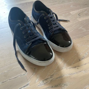 Lanvin Cap Toe marinblå - Mörkblå lanvins i lackad cap toe. Storleken är 42 ish. Mockan är dubbel impregnerad och glansen är insmord. Originalbox medföljer ej. Skriv gärna vid övriga frågor!