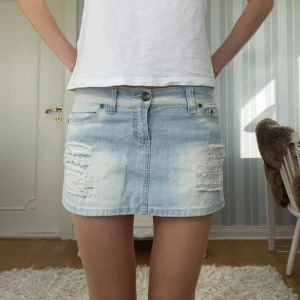 Ljusblå jeanskjol med slitningar - Snyggaste korta lågmidjade jeanskjolen! Perfekt nu till sommaren💕Midjemått: 42cm, längd: 29-32cm. Storlek M