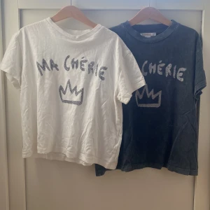 Ma Chérie t-shirt från Gina Tricot - Två coola t-shirts från Gina Tricot med trycket 'Ma Chérie' och en krona framtill. En är vit och en är mörkgrå, båda i mjuk bomull med rund hals och korta ärmar. Perfekt för dig som gillar grafiska prints och chill stil.