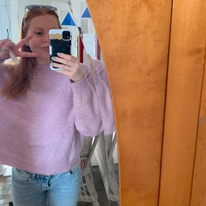 Ljuslila stickad tröja med loose fit - Supermysig ljuslila stickad tröja med loose fit och ribbade muddar vid hals, ärmslut och nederkant. Tröjan har en enkel design med rund hals och långa ärmar, perfekt att slänga på sig när det är lite kyligt ute. Passar dig som gillar chill och comfy vibes.