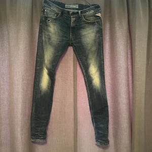 Replay jeans  - Ett par Replay jeans i modellen Jondrill. Jeansen har några stilrena slitningar och en tvättad design. De har tecken på användning med inget som påverkar helhetsintrycket. Storleken är W31/L32.