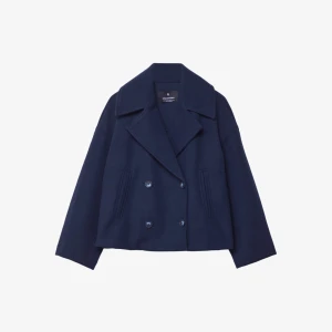 Marinblå kappa från Stradivarius - Säljer en marinblå skepparkavaj från Stradivarius i storlek XS. Jackan har dubbelknäppning med fyra knappar framtill, bred krage och två fickor. Materialet är mjukt och känns som ull, perfekt för kyliga dagar. Snygg loose passform och klassisk look.