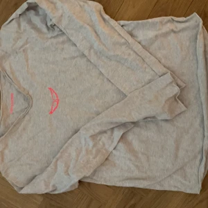 Grå långärmad tröja Zadig & Voltaire - Säljer en grå långärmad tröja från Zadig & Voltaire med coolt tryck på ryggen med döskalle, blommor och turnédatum. Tröjan har v-ringning med råa kanter och två knappar vid halsen. Materialet är mjuk bomull och trycket har inslag av rött, svart och lila.