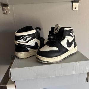  Nike Air Jordans 1 - Snygga sällsynta svartvita Nike Air Jordans med klassisk design. Skorna har snörning och en hög siluett som ger ett sportigt utseende. Perfekta för dig som vill ha en stilren look med en ikonisk touch. 