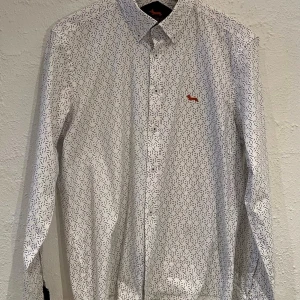 Harmont & Blaine - Slim fit - Strl XL - Vit Harmont & Blaine skjorta tillverkad helt i fin stretchad bomull. Skjortan har långa ärmar och interiör mörkblå manschetter , medan knapparna är prydda med märkets logotyp - 95% bomull och 5% Elastan - botton-down krage - slim fit passform