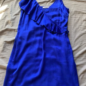 Blå klänning från NA-KD - Snygg blå klänning från NA-KD med volangdetalj och band som går att justera. Knappt använd och super bra skick!