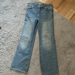 Blå jeans med fransad kant - Säljer ett par snygga blå jeans med fransad kant. De har en klassisk femficksdesign och en bekväm passform. Perfekta för en avslappnad stil.