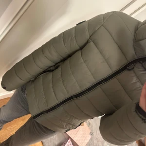 Grön dunjacka från Superdry - Säljer en superfin grön dunjacka från Superdry. Jackan har en dragkedja framtill,  luva och en normal passform. Den är knappt använd och  perfekt om man inte vill frysa utomhus. Köpte den för ca 1400 kr , med tanke på att den knappt är använd så är den i bra skick . Pris kan diskuteras 
